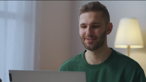 cheerful-smiling-man-is-greeting-participants-of-online-video-chat-waving-hand-to-web-camera-male-portrait-in-living-room-distant-working-meeting